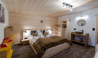 A cozy bedroom with wood paneling and a large bed. The decor is modern and inviting, with warm colors.