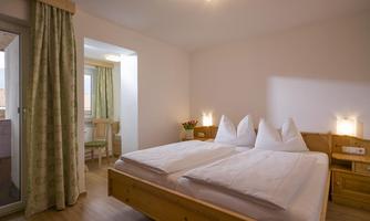 Bedroom with double bed, TV, and its own small balcony.