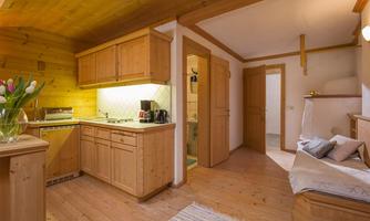A cozy kitchen made of light wood with modern appliances and plenty of storage space. The room has a warm, inviting character and is part of a rustic living area.
