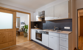 A modern kitchen with gray cabinets and wood accents. It is open to the adjacent living area and feels inviting and bright.