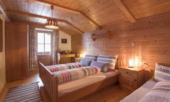 A cozy bedroom with two wooden beds. The walls are made of wood and the room has a warm, inviting atmosphere.