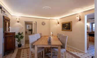 A stylish dining area with a wooden table and modern chairs. The walls are painted in warm tones and softly lit.