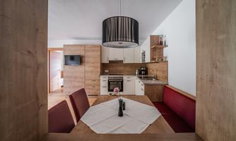 A modern kitchen with wooden details and a dining table. The decor is bright and inviting, perfect for social evenings.