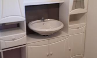 A modern bathroom furniture with a sink and plenty of storage space. The walls are painted purple, and the floor is tiled with gray tiles.