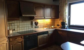 A cozy kitchen with dark wood and a large window. The features include a stove, a sink, and various kitchen appliances.