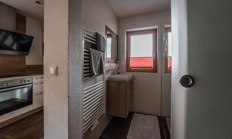 A modern bathroom with a sink and towel holders. There are large windows that let in natural light.