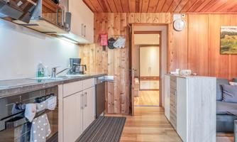 A modern kitchen with wooden cladding and an elegant design. The space is well-lit and has a cozy living area.