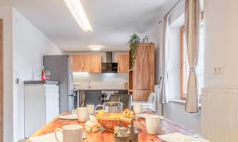 A modern kitchen with a large wooden table and an inviting decor. The table is lovingly set and offers space for several people.
