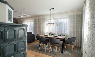 A modern dining room with a large table and elegant chairs. The walls are adorned with curtains and decorative elements.