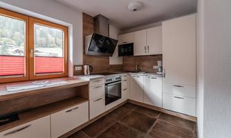 A modern kitchen with bright cabinets and a spacious work surface. Large windows provide plenty of natural light and a view outside.