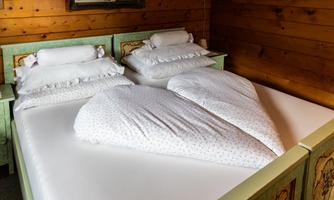 A cozy double bed with two combined blankets in heart shape. The room has a rustic wood decor and conveys a romantic atmosphere.