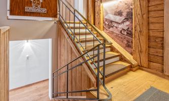An inviting wooden staircase with a modern railing. Pictures and signage of the holiday farm are mounted on the wall.