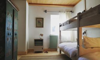 A cozy room with a bunk bed and a wooden floor. The room has a window with a bright curtain and an attractive decoration.