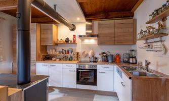 A modern kitchen with wooden and white furniture. It is well-equipped and offers plenty of storage space.