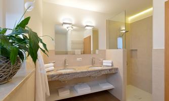 Modern bathroom with double sink, large shower, toilet, and towel warmer.