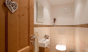 A modern bathroom with wood paneling and a beautiful mirror. It is bright and cozy, with clean white and clear lines.