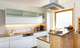 A modern kitchen with bright cabinets and a large window front. The room is bright and inviting, with a wooden countertop and stainless steel appliances.