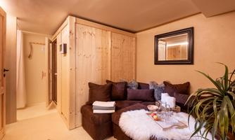 A cozy living space with a dark brown sofa and a soft, white rug. Wood paneling and a mirror give the room a warm atmosphere.