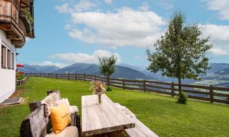 A cozy table outside with a view of green meadows and mountains. The surrounding area is quiet and inviting, ideal for relaxing hours in nature.