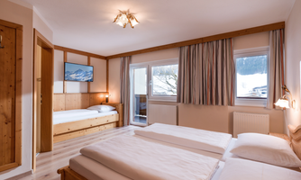 The bedroom is equipped with a large double bed as well as a single bed. The modern bathroom features a shower, toilet, and a towel warmer. There is direct access to the balcony from the room.