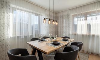 A modern designed dining area with a wooden table and six chairs. Large windows provide plenty of daylight and an inviting atmosphere.