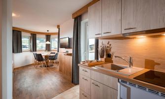 Bright, open living-sleeping area with kitchenette, cozy dining area, double bed, and TV.