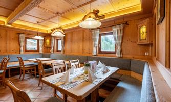 A cozy restaurant with wooden paneled walls and warm lighting. Several tables with lovingly set places and decorative elements.
