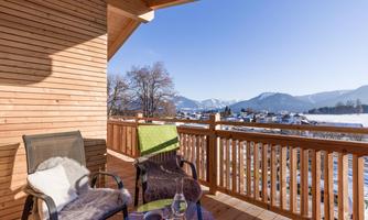 A cozy balcony with two chairs and a clear view of the mountains. The wooden cladding creates a warm atmosphere.