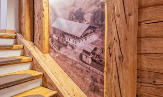 A staircase with wooden steps and a picture of a historic barn on the wall. The surroundings are rustic and inviting.