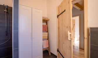 A modern bathroom with a shower and a white cabinet. The wooden details and towels create a cozy atmosphere.