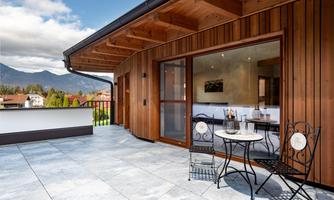A modern terrace with wood paneling and a view of the mountains. A small table with chairs invites you to relax.