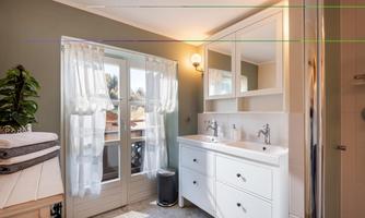 A modern bathroom with a shower and a double sink. Large windows let in plenty of natural light and create an inviting atmosphere.