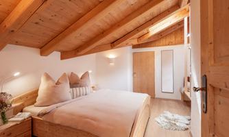 A cozy bedroom with a wooden ceiling and a large bed. Bright colors and a calm atmosphere create a relaxing environment.