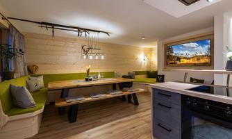 A cozy dining area with wooden decor and green seat cushions. Large window with a view of the mountains provides plenty of light.