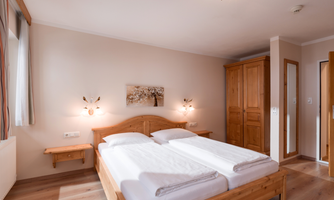 The bedroom is equipped with a double bed, a single bed, and a TV. The bathroom has a shower, toilet, and a towel warmer. There is direct access to the balcony from the room.