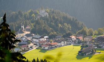 A picturesque mountain landscape with a small village and a church on a hill. Surrounded by forests and meadows, the scene radiates tranquility and idyll.