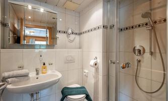 A modern bathroom with a shower, sink, and toilet. The walls are brightly tiled and provide a clean, inviting atmosphere.