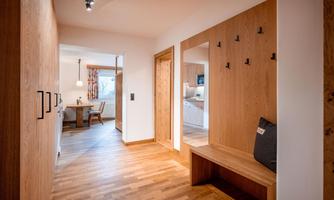 A bright hallway with wardrobes. In the background, a cozy dining area is visible.