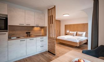 A modern kitchen-living room with a dining area and a double bed.