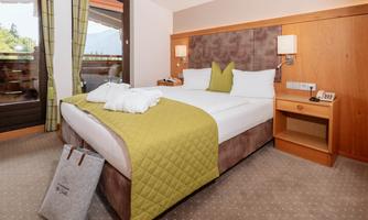 A modern hotel room with a comfortable bed and bright interior. The large windows offer a view of the surroundings.