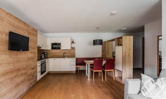 A modern kitchen-dining area with wooden paneling and elegant furniture. The space is bright and inviting, ideal for social gatherings.