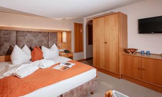 A cozy hotel room with a large bed and rustic wooden furniture. The room is bright and inviting, with modern comfort.