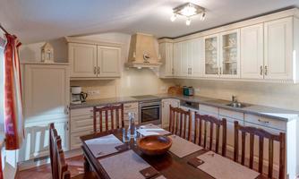 A bright kitchen with white cabinets and a large dining table. It is well equipped with modern appliances and has an inviting atmosphere.