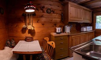 A cozy wooden kitchen with a table and chairs. The decor is rustic with a warm atmosphere and a window that lets in light.