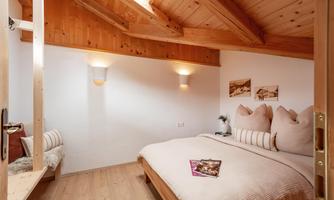 A cozy bedroom with a large bed and wooden walls. The atmosphere is warm and inviting, perfect for relaxing.