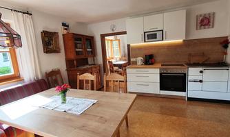 A cozy kitchen with dining area and wood stove. Bright walls and windows create a friendly atmosphere.