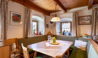 A cozy dining area with a wooden ceiling and an inviting seating area. There is a green decoration and a glass bottle on the table.