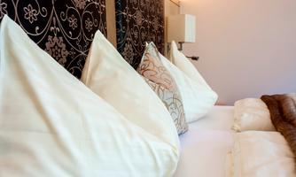 A cozy bed with a array of pillows. The background is elegant with stylish wall paneling.