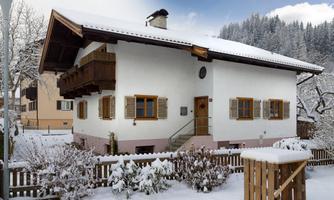 A cozy house in the snow with a balcony and warm colors. The garden is covered with fresh snow and offers an inviting atmosphere.