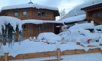 A snow-covered wooden house with a large, white garden. The surroundings are quiet and wintry.